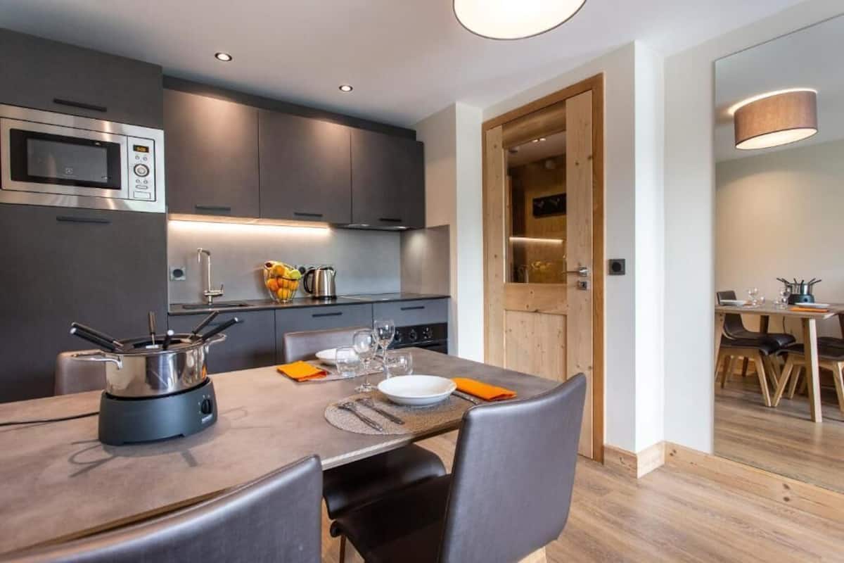 A modern kitchen with a built-in microwave, a stove, and a dining area with a table set for two.