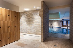 Une salle de bain moderne avec un mur en pierre, un meuble en bois et un espace piscine.