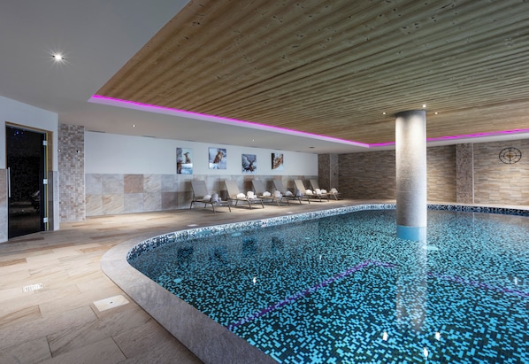 A modern indoor swimming pool with a wooden ceiling, tiled walls, and lounge chairs. - Residence Daria-i Nor (Huez)