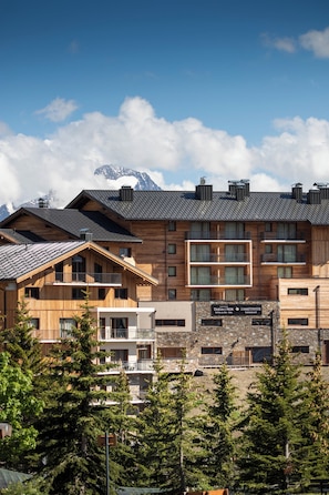 Un immeuble à plusieurs étages, doté d’une façade en bois, de balcons et d’une enseigne indiquant la présence d’un restaurant.