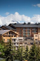 Un hôtel à plusieurs étages, doté d’une façade en bois et de balcons, et comprenant un restaurant et un spa.