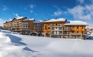 Un hotel de varios pisos con fachada de madera y balcones, ubicado en un paisaje nevado.