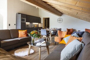 A modern living room with a sofa, coffee table, and a dining area with chairs and a table set for a meal.