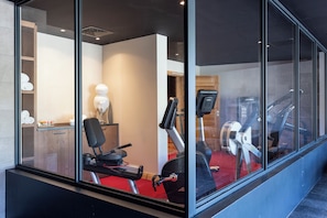 Un gimnasio con equipamiento de ejercicio, una cinta de correr y una bicicleta estática.