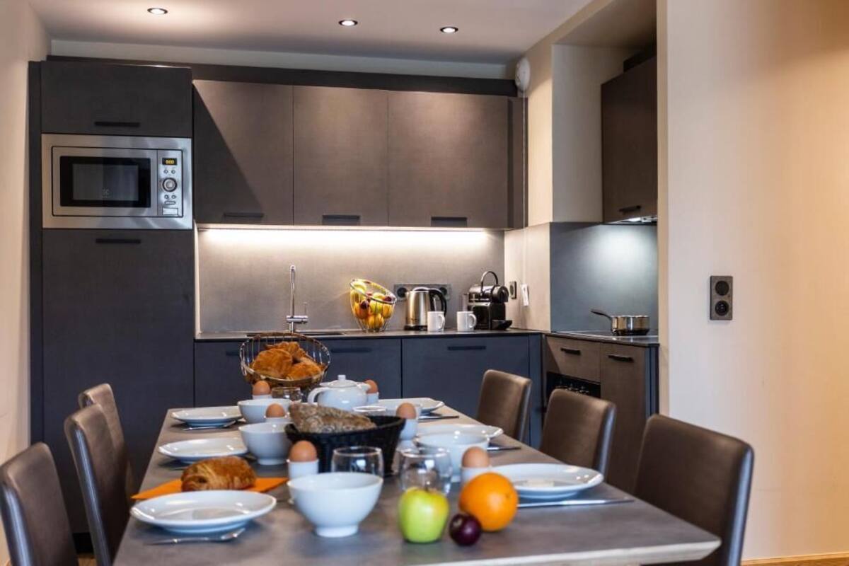 A modern kitchen with a built-in microwave, a coffee machine, and a fruit bowl on the counter.
