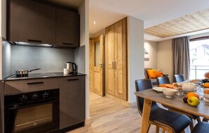 A modern kitchen with dark cabinetry, a stove, and a dining area with a table set for two.