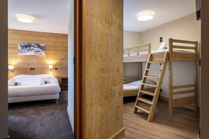 A room with a bunk bed, a ladder, a bed with white bedding, a wooden wall panel, and a painting on the wall. - Residence Daria-i Nor (Huez)