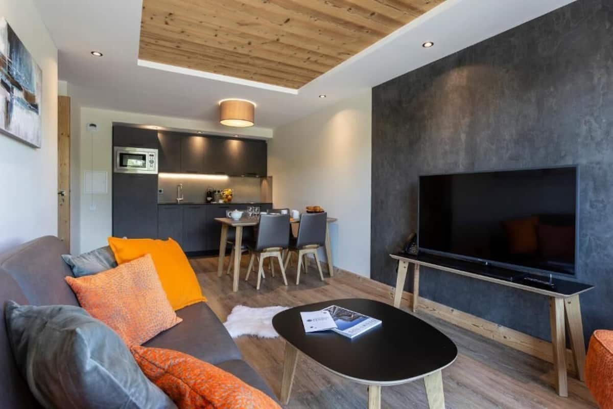 A modern living area with a sofa, coffee table, and a flat-screen TV.