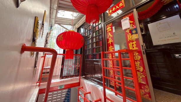 Een gang met rode lantaarns, een trap en een bord met Chinese karakters.
