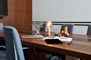 A conference room with a wooden table, a laptop, a tablet, a smartphone, a vase with flowers, a decorative globe, and wooden blocks. - Form Hotel Dubai (Dubai)