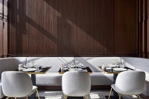 A dining area with a sofa, three chairs, and a table set with plates, glasses, and cutlery. - Form Hotel Dubai (Dubai)