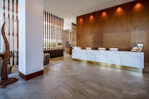 A reception desk with a marble top, wooden paneling on the wall, and a modern interior design. - Form Hotel Dubai (Dubai)