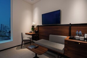 A modern hotel room with a sofa, a small desk with a plant, a coffee maker, and a large window with a city view. - Form Hotel Dubai (Dubai)