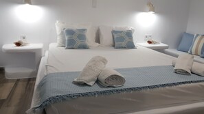 A hotel room with a bed, two bedside tables, and a nightstand. - Iris Boutique Hotel (Paros)