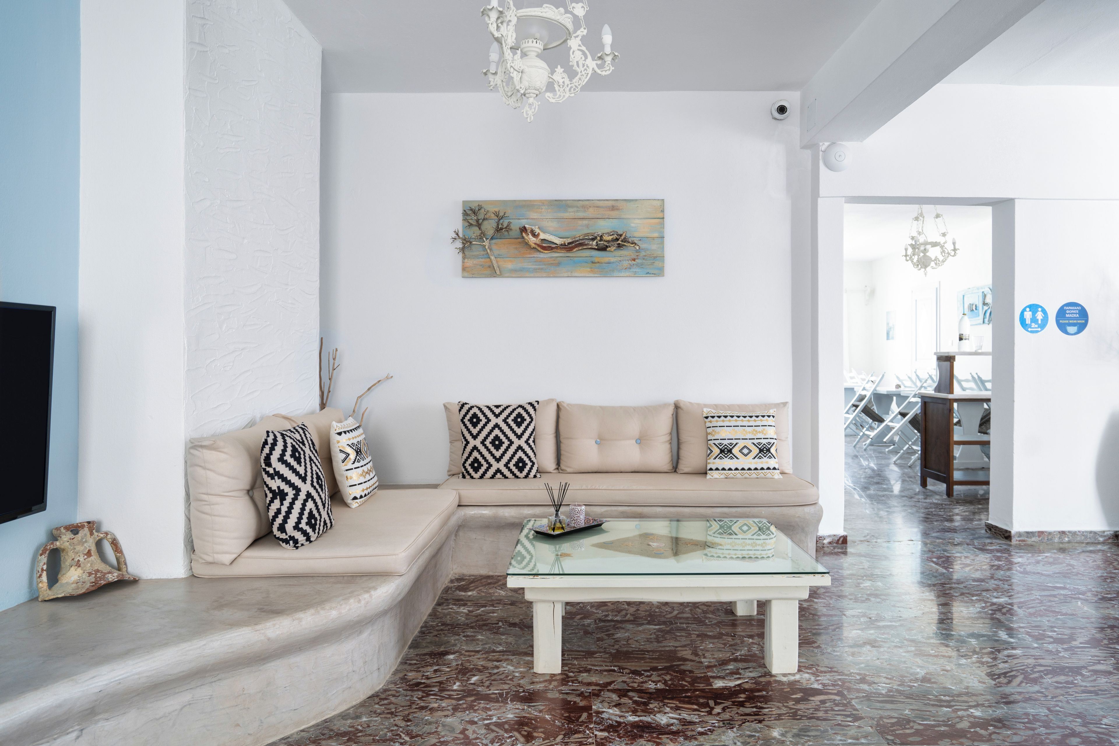 A living room with a beige sectional sofa, a glass coffee table, and a decorative painting on the wall.