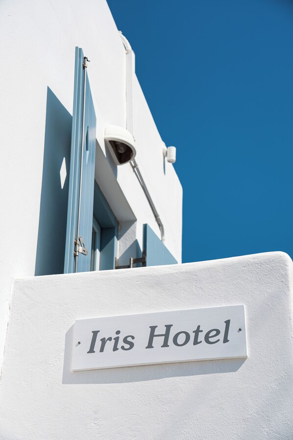 A hotel sign with the name 'Iris Hotel' mounted on a white wall.
