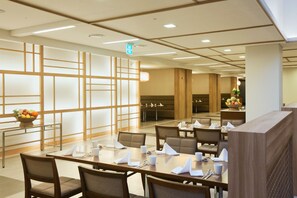 A hotel dining area with multiple tables, chairs, and a fruit bowl.