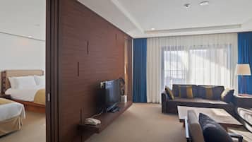 A hotel room with a bed, a TV, a sofa, and a desk.