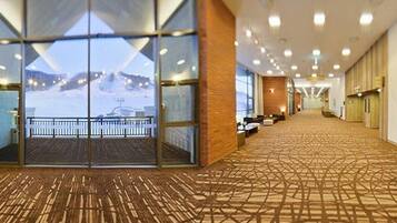 A hotel lobby with a patterned carpet, a reception desk, and a view of a snowy landscape through large windows.