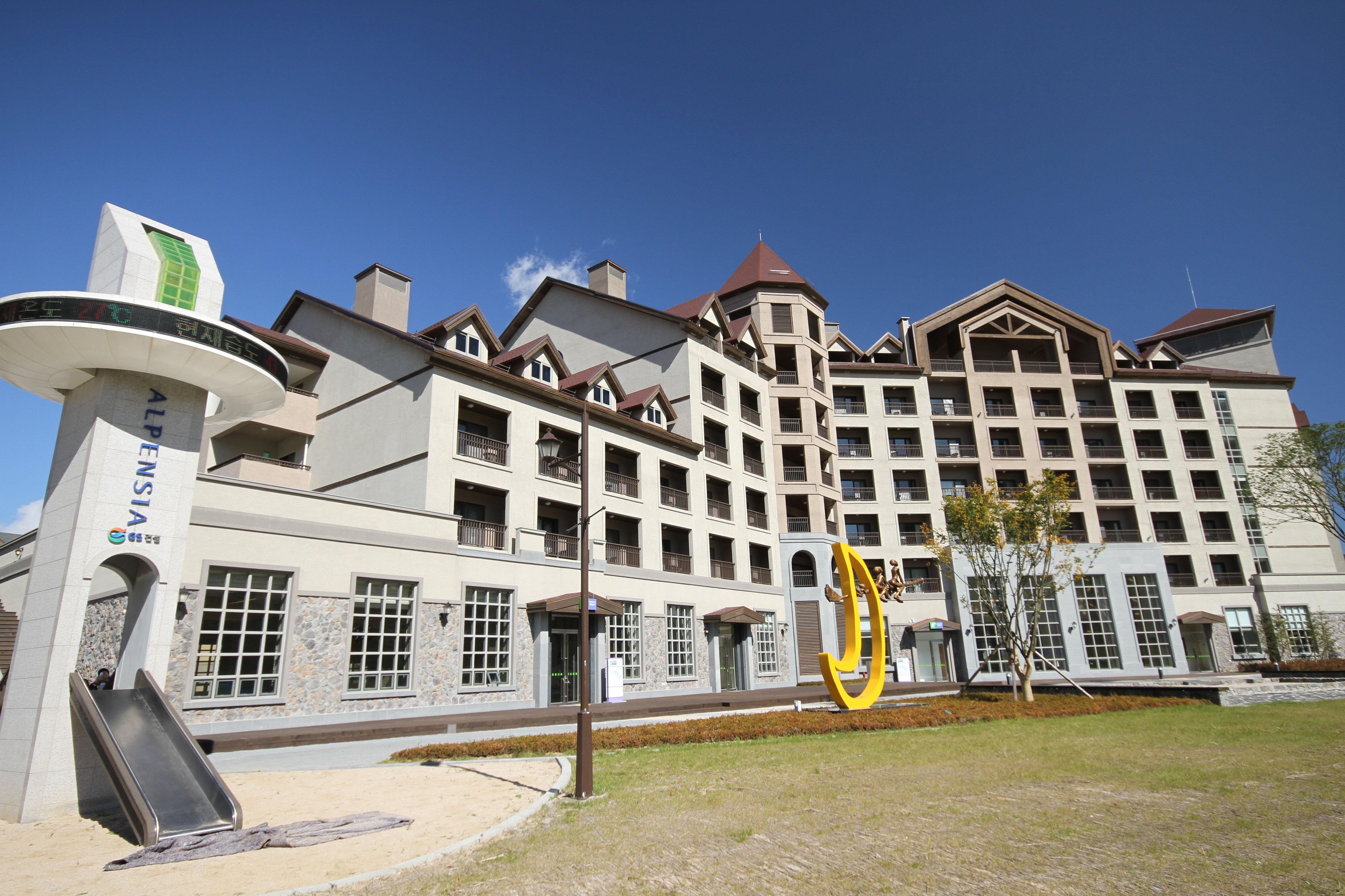 A multi-story hotel with a central atrium, balconies, and a prominent entrance with a sign.