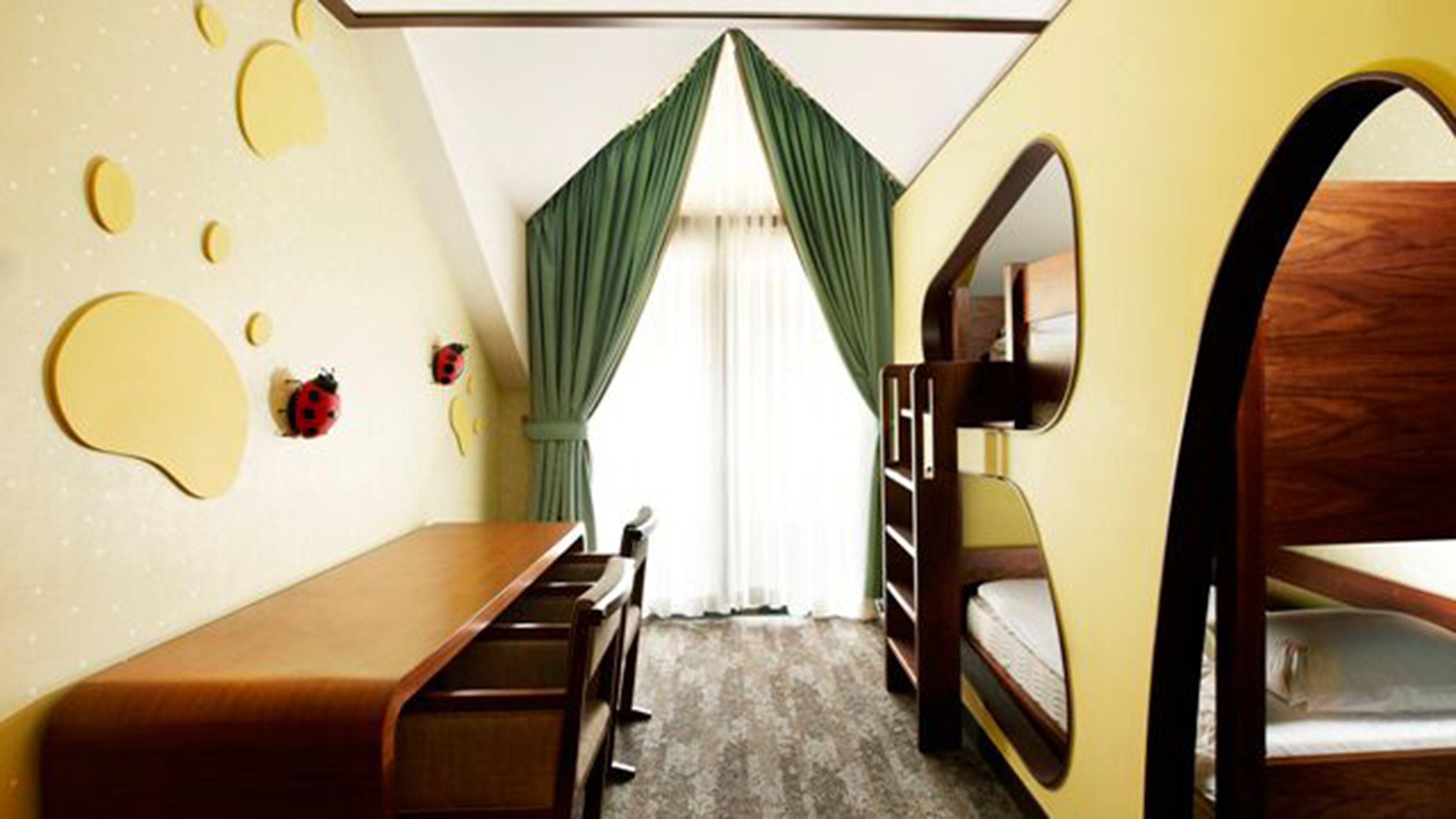 A room with bunk beds, a desk, and a mirror.