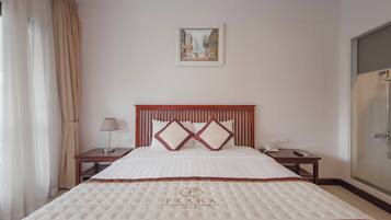 A hotel room with a large bed, a nightstand, a lamp, a framed picture on the wall, and a shower area.