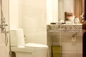 Un baño con inodoro, ducha y lavamanos con encimera de granito.
