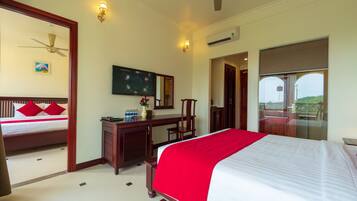 A hotel room with a bed, a desk, a television, and a balcony with a view.