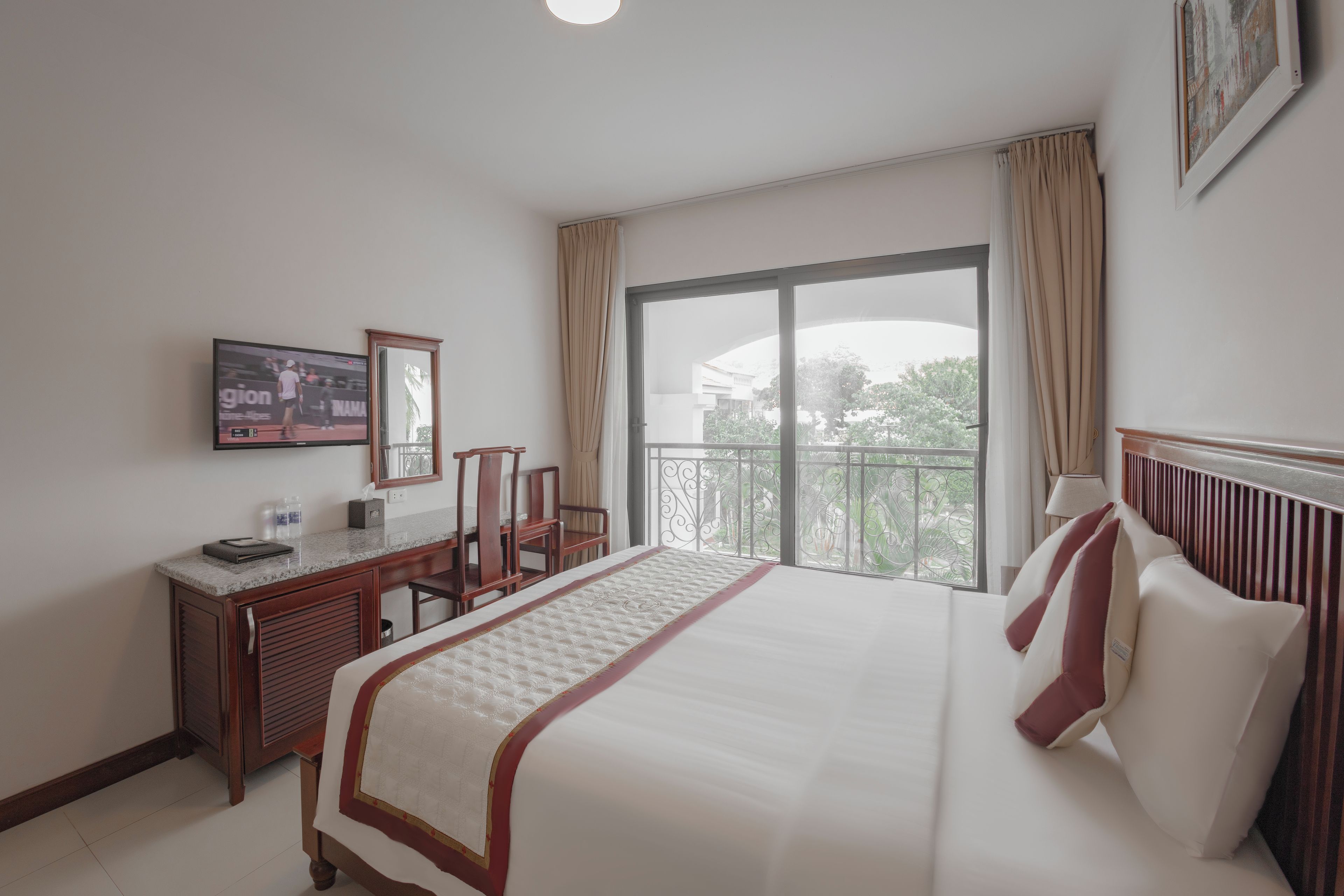 A hotel room with a bed, a desk, a chair, a television, and a large window with a view.