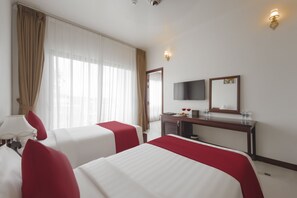Quarto de hotel com duas camas, uma escrivaninha, um espelho e uma janela com cortinas.