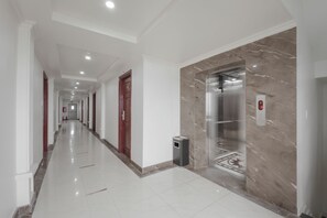 A long, well-lit hallway with a marble wall and an elevator. - Praha Hotel Phu Quoc (Phu Quoc)