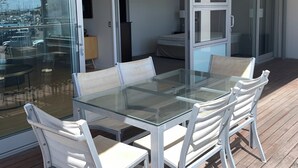 A glass-enclosed patio with a table and chairs, a sliding glass door leading to an interior room, and a view of the outside. - Location, location, location - as good as it gets in Napier (Napier)