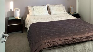 A bedroom with a bed, nightstands, a lamp, and a door. - Location, location, location - as good as it gets in Napier (Napier)