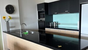 A modern kitchen with a central island, black cabinets, and a light-colored countertop. - Location, location, location - as good as it gets in Napier (Napier)