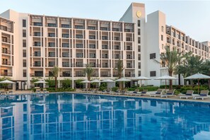 Un hôtel doté d’une piscine, de chaises longues et de palmiers.