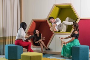 A modern interior with geometric seating and a person using a laptop. - Intercontinental Fujairah Resort (FUJAIRAH)