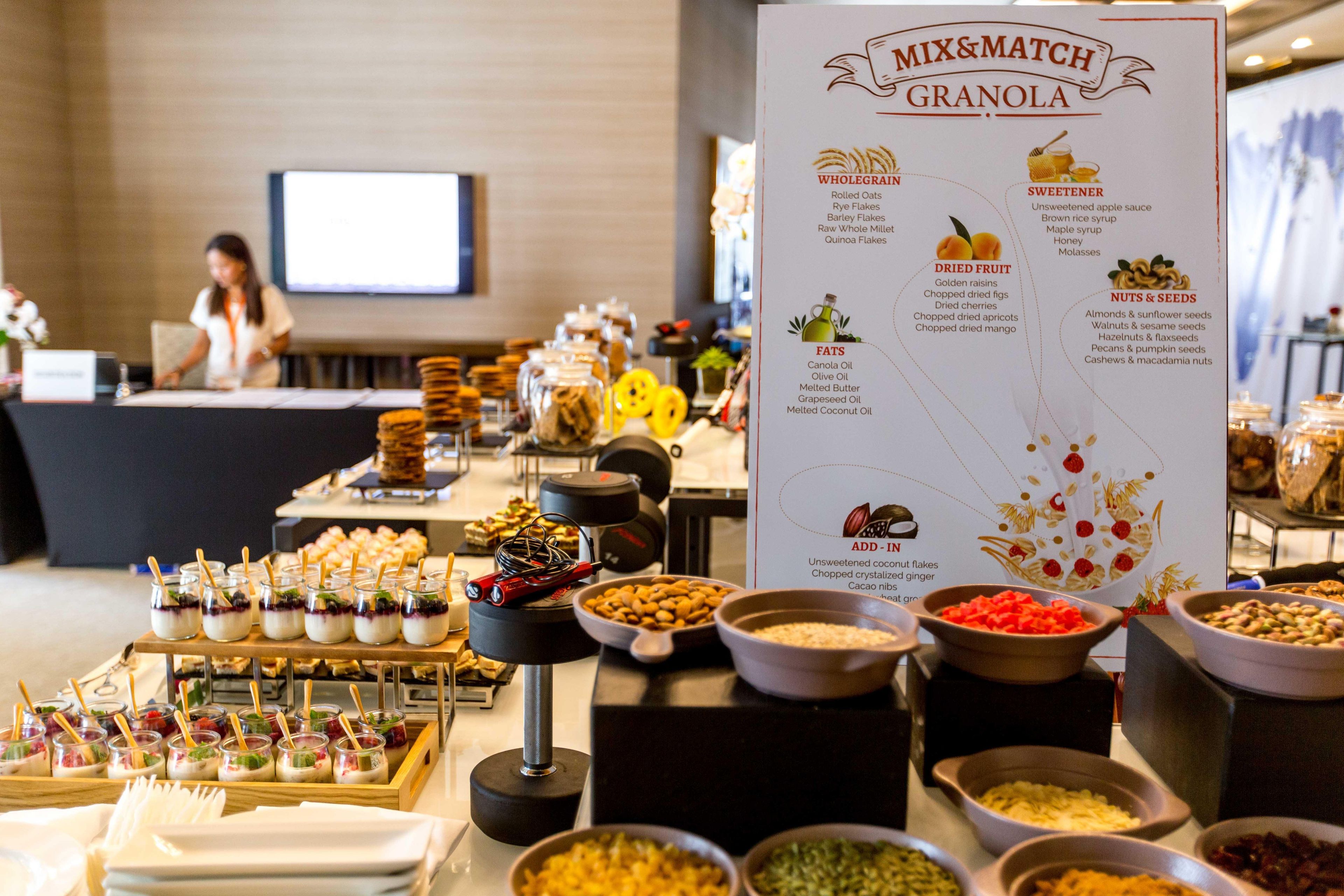 A buffet setup with various food categories and a sign detailing the mix and match granola options.