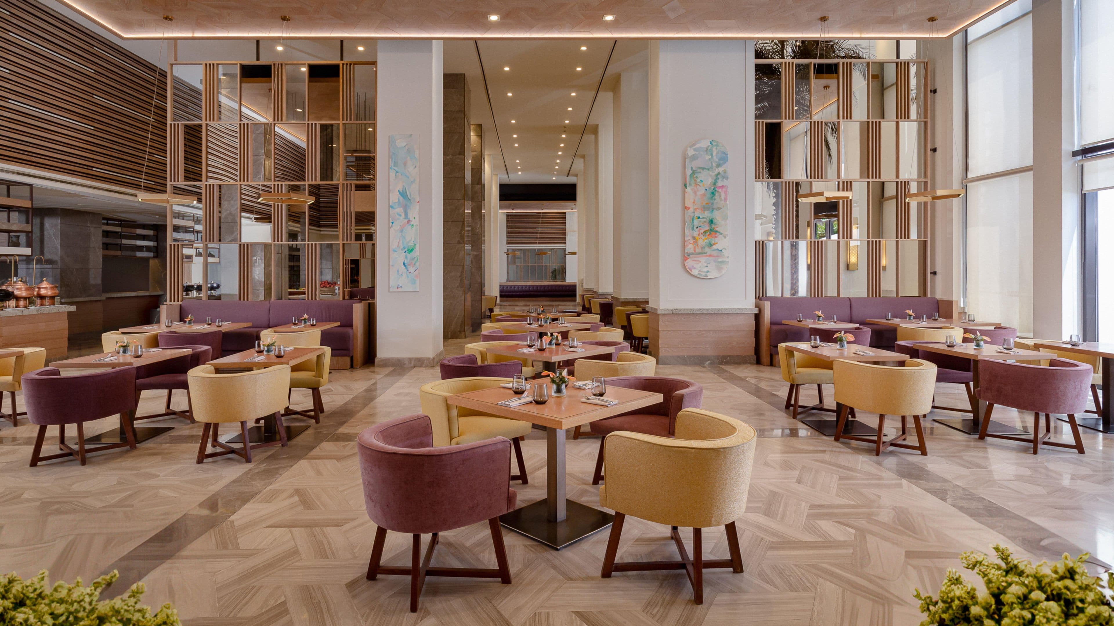 Un interior de restaurante moderno con varias zonas de estar, incluyendo reservados y mesas, y un pasillo central.