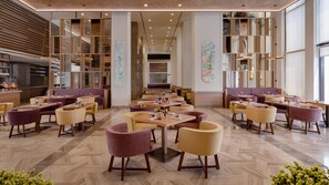 Un interior de restaurante moderno con varias zonas de estar, incluyendo reservados y mesas, y un pasillo central.