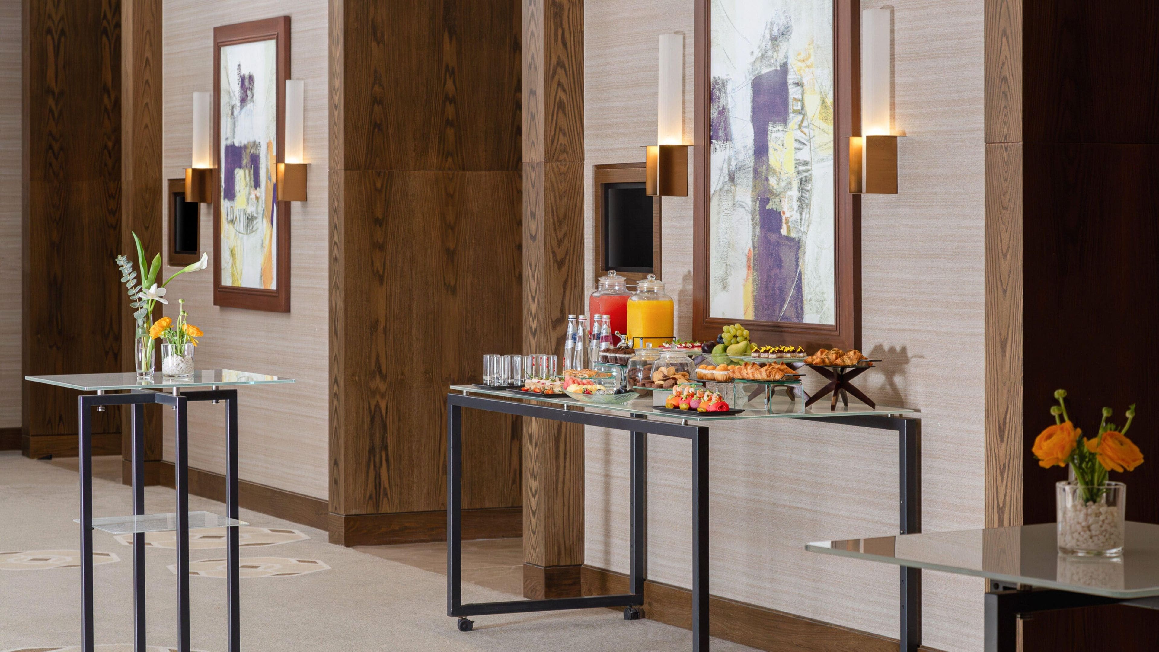 Habitación de hotel con bufé de desayuno, paredes de paneles de madera y obras de arte.