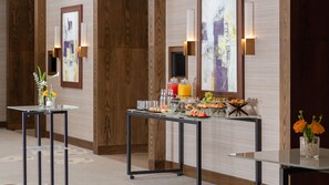 A hotel room with a breakfast buffet, wooden panel walls, and artwork. - Intercontinental Fujairah Resort (FUJAIRAH)