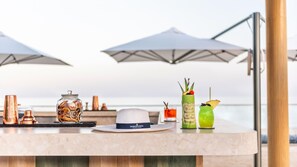 A bar area with a hat, a glass jar, and two cocktails. - Intercontinental Fujairah Resort (FUJAIRAH)