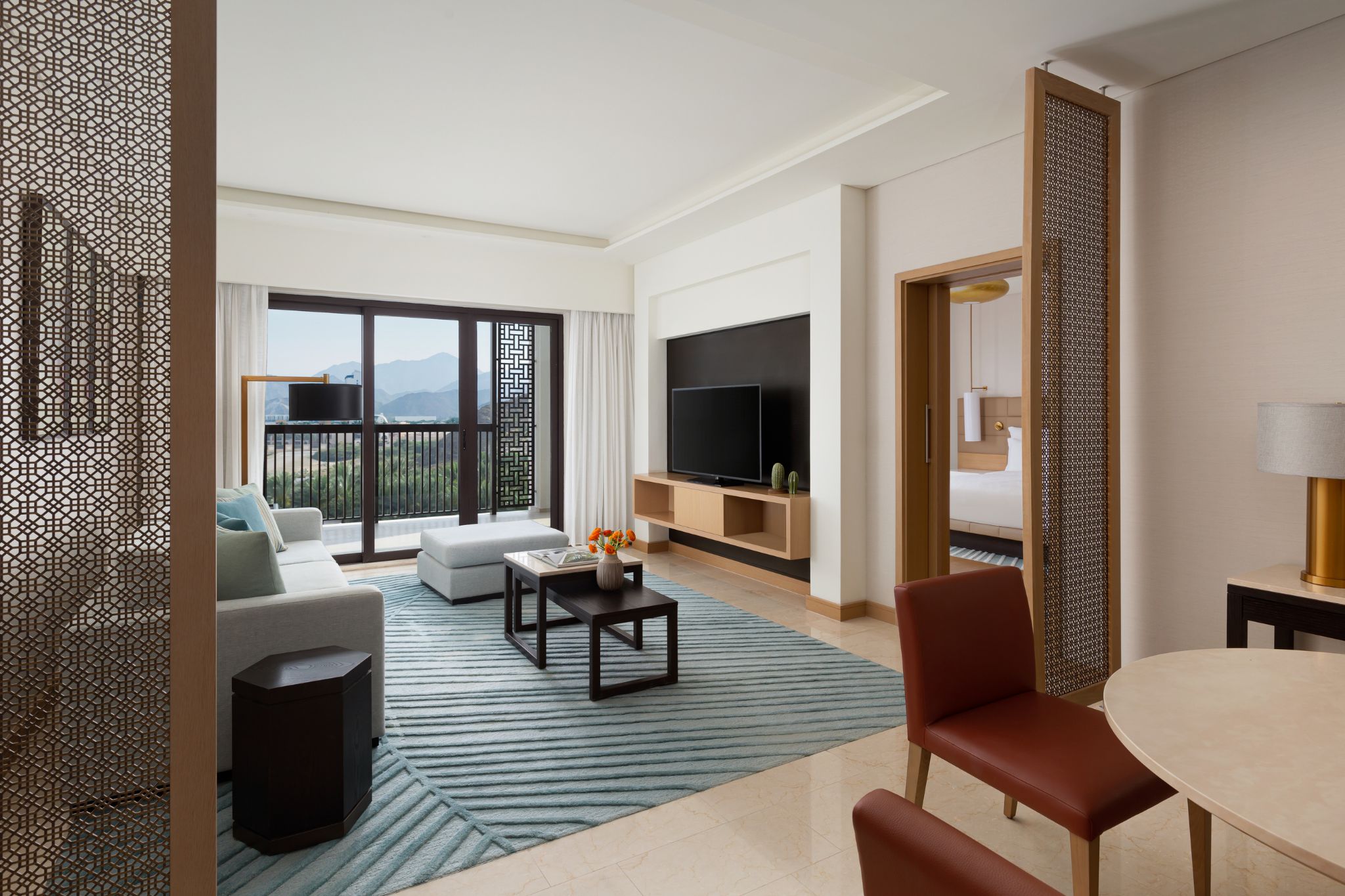 Une chambre d’hôtel avec balcon, une télévision à écran plat, un canapé, une table basse et un coin repas.