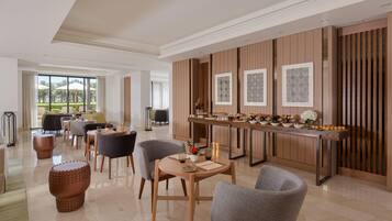 Een moderne hotel lobby met een eetgedeelte, een receptiebalie en uitzicht op de omgeving.