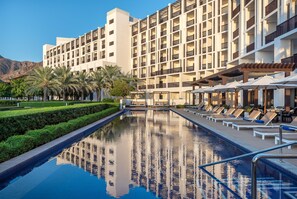 A hotel with a swimming pool, lounge chairs, and a mountain backdrop. - Intercontinental Fujairah Resort (FUJAIRAH)