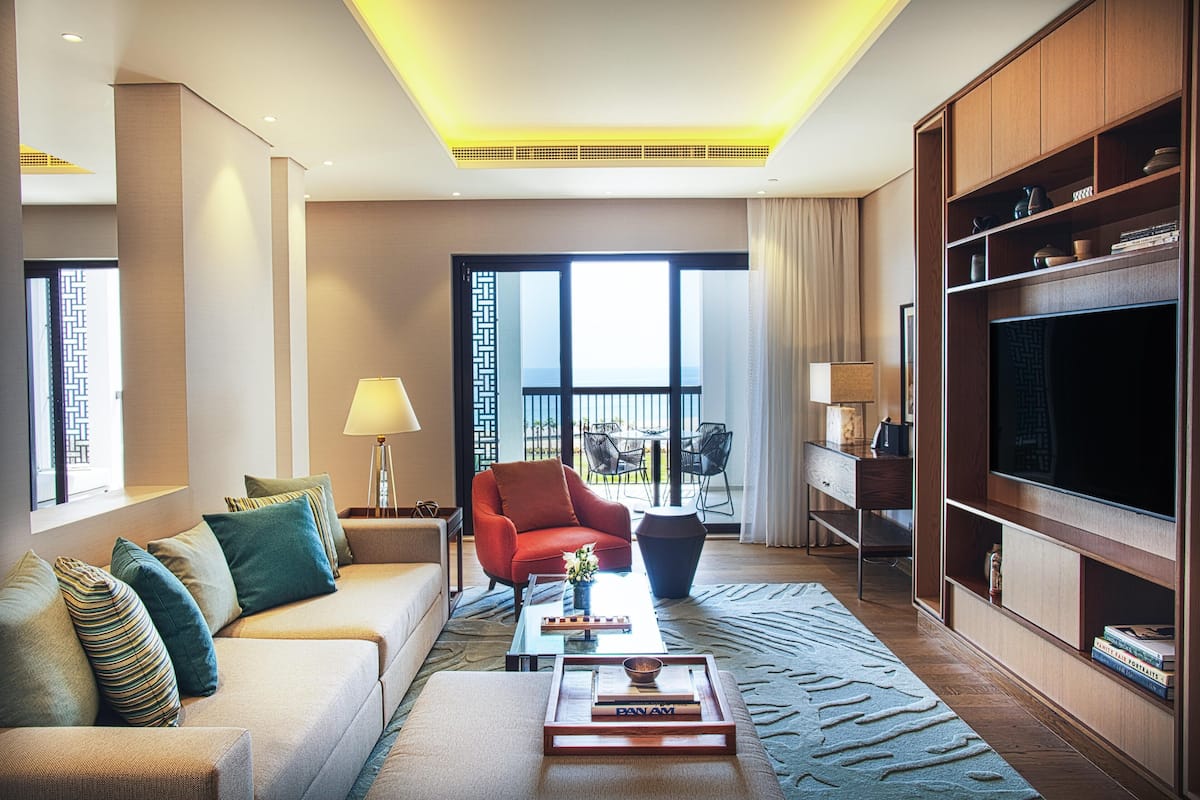 A modern living room with a sofa, armchair, coffee table, and a TV on a wooden cabinet.