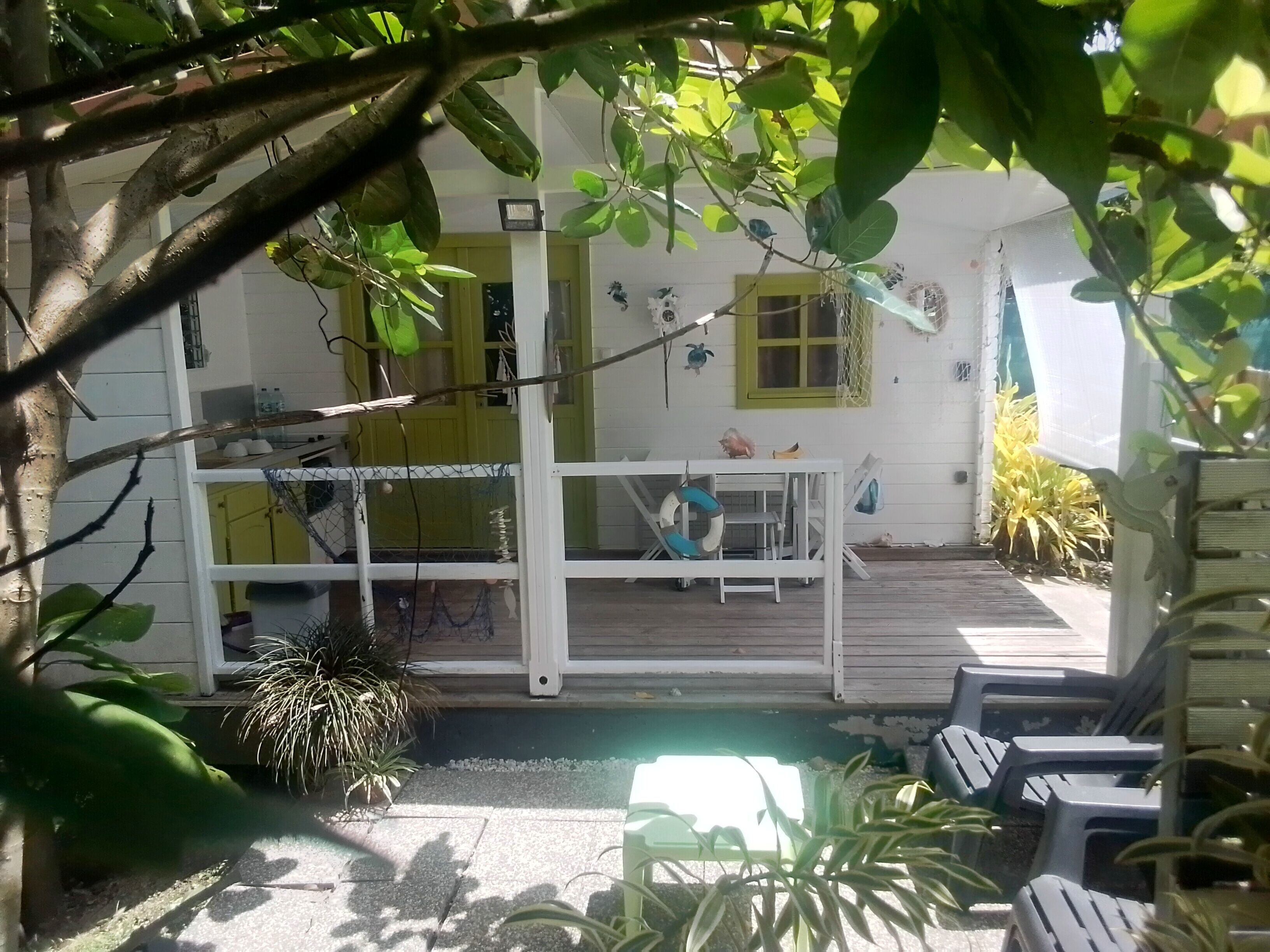 Een huis met een veranda, een tafel en stoelen.