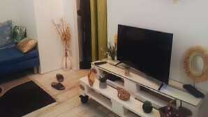 Ein Wohnzimmer mit Fernseher auf einem Schrank, einem blauen Sofa und Wanddekorationen.