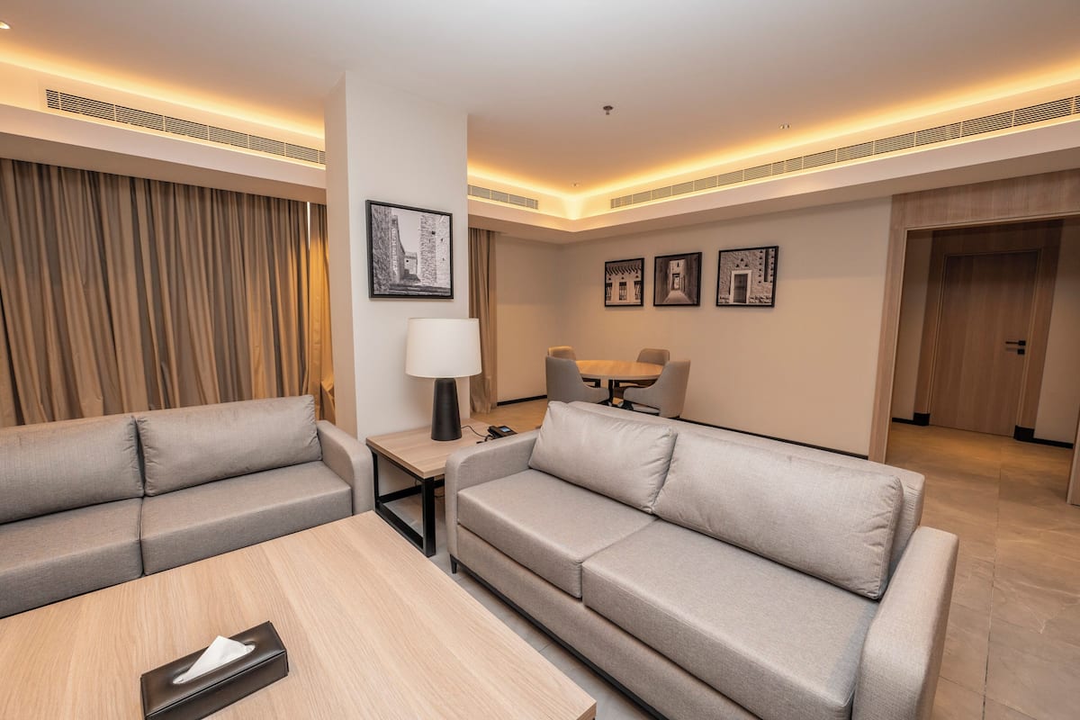 Une chambre d’hôtel moderne équipée d’un canapé, d’une petite table, d’une lampe et d’un coin repas avec des chaises.