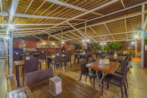 Un comedor interior con mesas y sillas, una pared de ladrillo y una estructura de techo de madera.